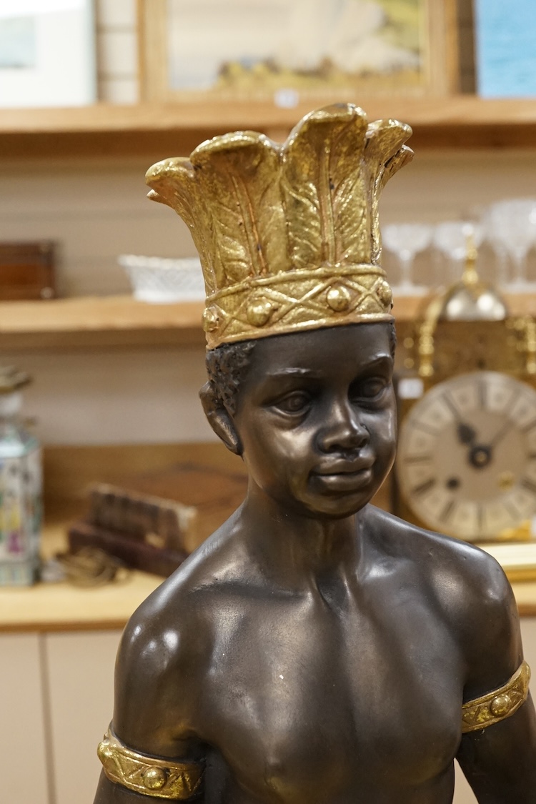 A gilded resin model of an Nubian boy holding a shell and wearing a crown, 65cm high.